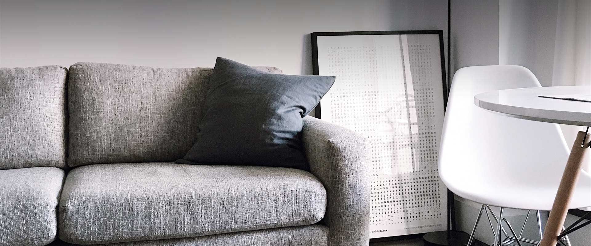 Grey couch and black throw pillow is next and white table with white chair in a modern living space.